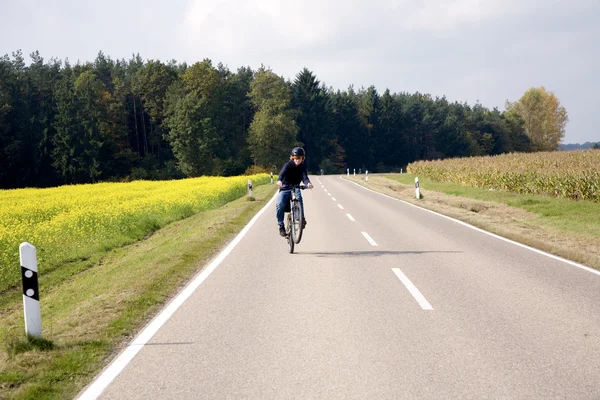 Menino em sua bicicleta de montanha está em um passeio de bicicleta ao longo beauti — Fotografia de Stock