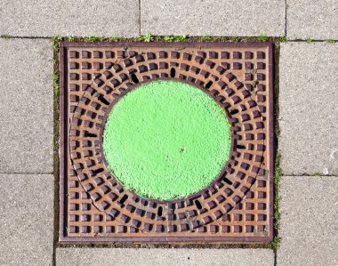 A manhole cover in the street to enter the canalisation clipart