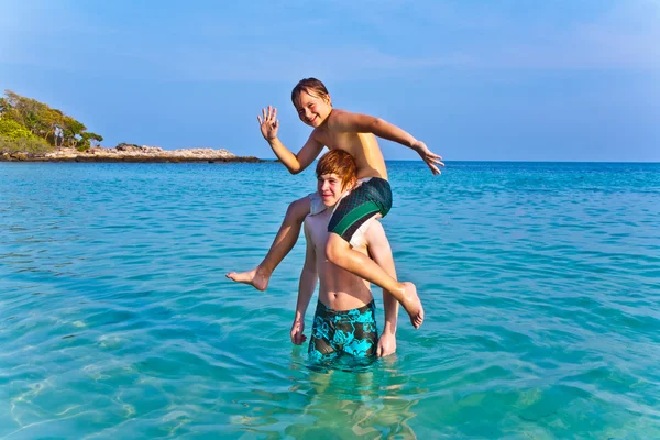 Bröderna spelar tillsammans i det vackra havet med kristallklart vatten en — Stockfoto