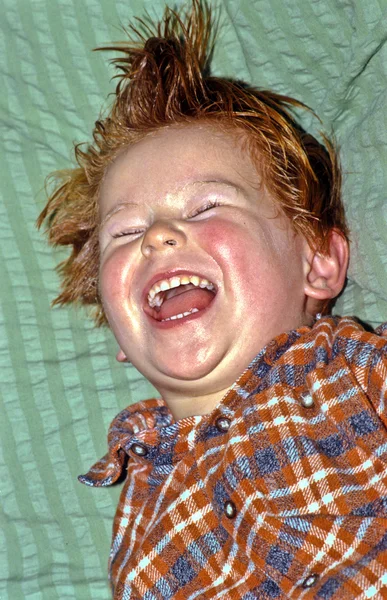 Retrato de bonito bpy deitado em seu cobertor e ri — Fotografia de Stock