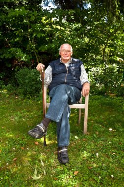 Portrait of elderly man sitting happy in his garden clipart