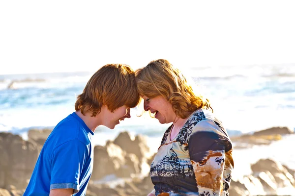 Счастливые мать и сын обнимаются на пляже — стоковое фото