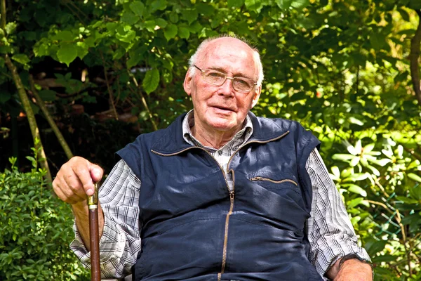 Retrato de homem idoso sentado feliz em seu jardim — Fotografia de Stock