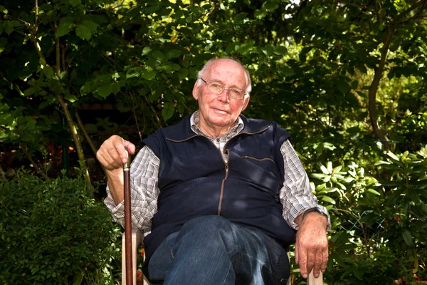 Retrato del anciano sentado feliz en su jardín — Foto de Stock