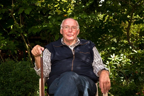 Портрет літнього чоловіка, що сидить щасливим у своєму саду — стокове фото