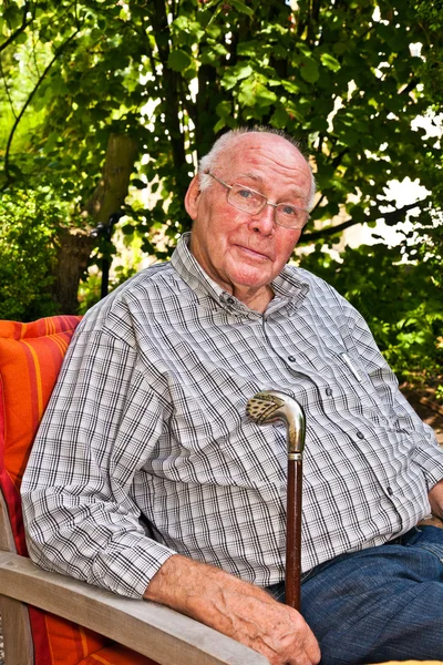 Homem idoso feliz em sua cadeira no jardim — Fotografia de Stock