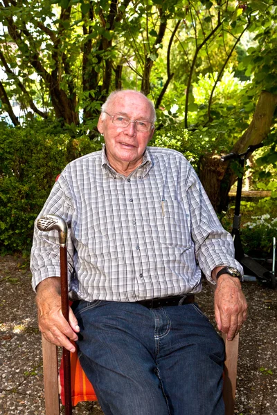 Glücklicher älterer Mann in seinem Stuhl im Garten — Stockfoto