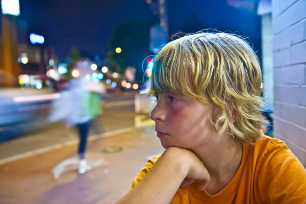 Netter Junge lächelt müde, während er nachts draußen sitzt — Stockfoto