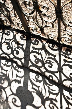 Wrought iron door to the garden with beautiful shadow near villa clipart