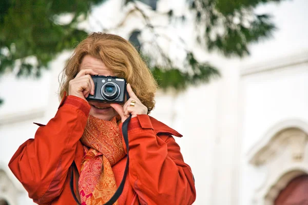 Nice lady with red hair, tourist, takes pictures of a historic — Stock Photo, Image