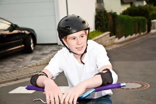 Счастливый улыбчивый мальчик в шлеме, гордящийся своими трюками BMX — стоковое фото