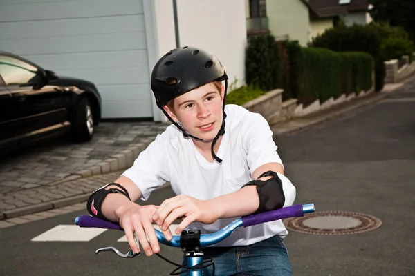 幸福微笑的男孩与盔甲，骄傲的他小轮车特技 — 图库照片
