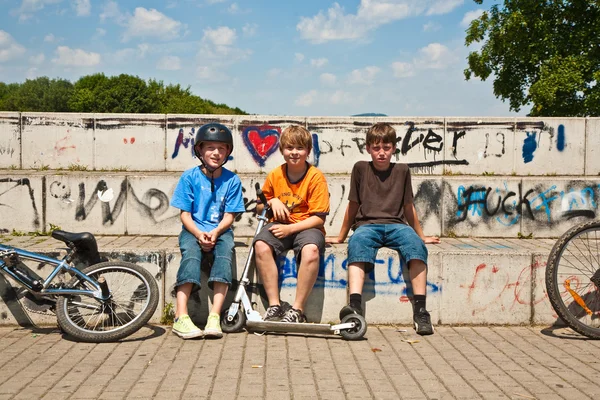 तीन मित्र विश्रांती आणि स्केट पार्क येथे ठोस खंडपीठावर बसून — स्टॉक फोटो, इमेज