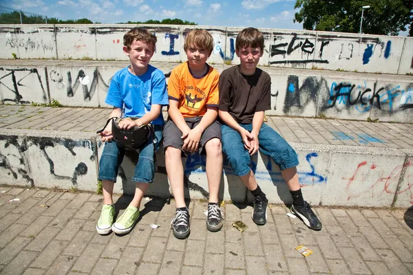 Three friends relaxing and sitting on a concrete bench at the skate park — Stock Photo, Image