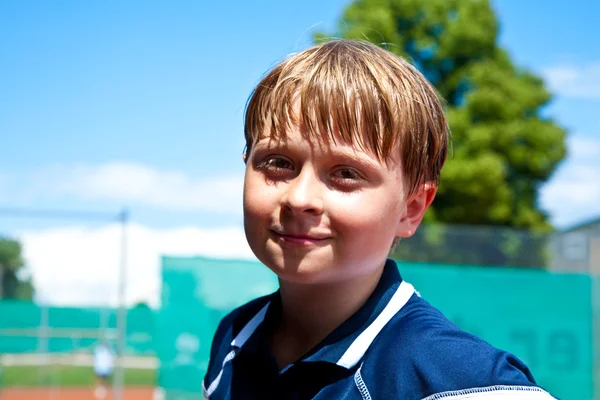 Criança parece feliz e satisfeito após o jogo de tênis — Fotografia de Stock