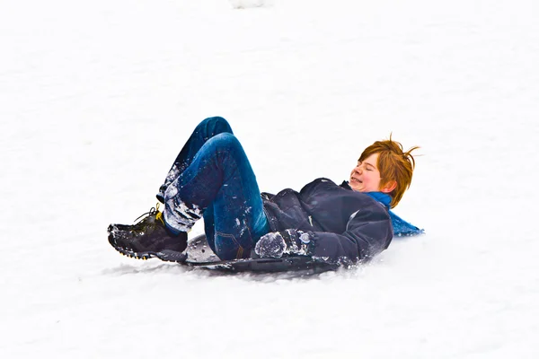 Criança escorregando pela colina abaixo na neve — Fotografia de Stock