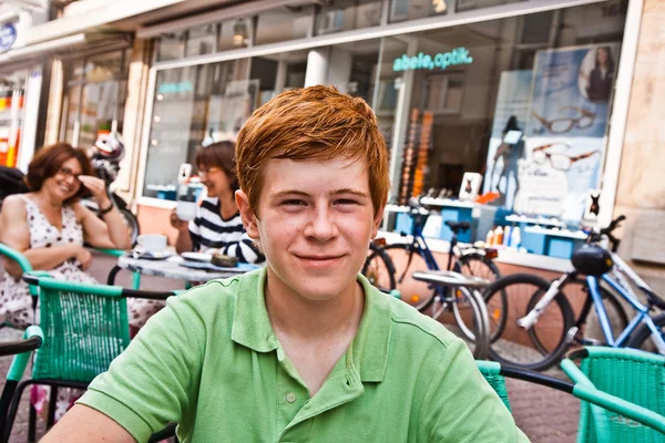 Niño con el pelo rojo se ve feliz y amigable sentado en una o — Foto de Stock