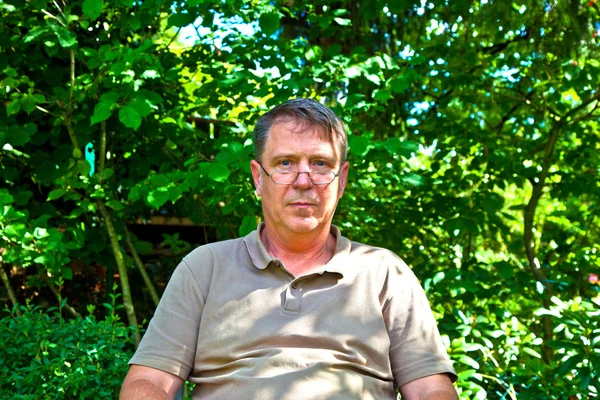 Bahçesini bir ağacın altında oturuyor ve dostça adam — Stok fotoğraf
