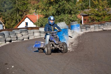 Child loves to race with a quad bike at the muddy quad track clipart