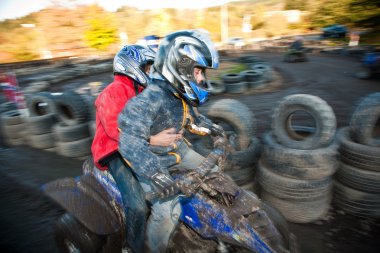 Child loves to race with a quad bike at the muddy quad track clipart