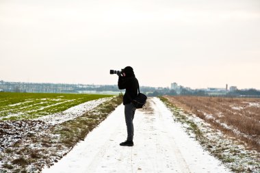 çocuk, doğada kışın bir fotoğraf çeker.