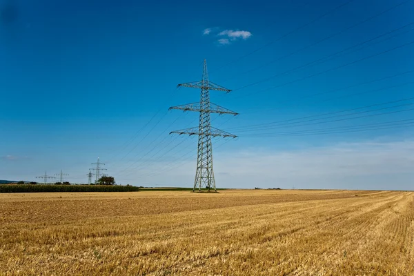 Věž za elektřinu v krásné krajině s zlatém poli — Stock fotografie