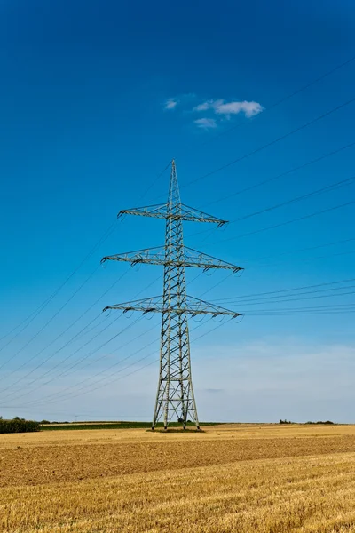 Torre per l'elettricità in un bellissimo paesaggio con campi dorati — Foto Stock