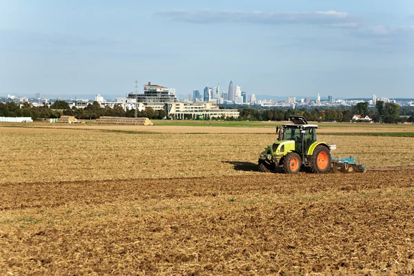 Traktor está correndo no acre arar a terra em luz dourada — Fotografia de Stock