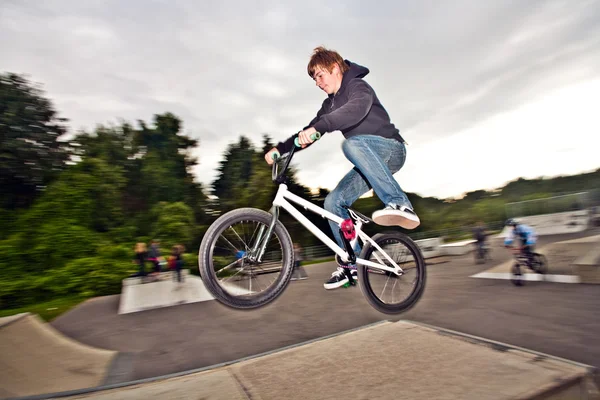 Joung red haired boy is jumping with his BMX Bike at the skate park — Stock Photo, Image