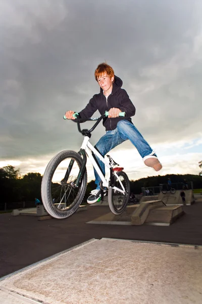 Joung рыжий мальчик прыгает со своим BMX велосипед в скейт-парке — стоковое фото