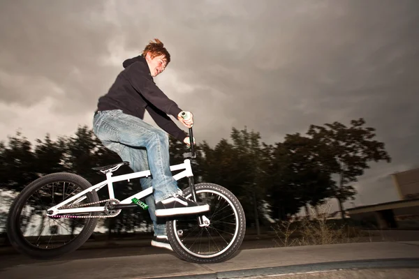 Joung red haired boy is jumping with his BMX Bike at the skate park — Stock Photo, Image