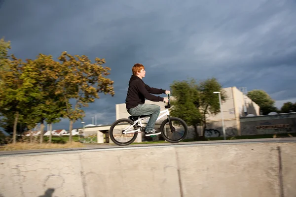 Le garçon aux cheveux roux saute avec son vélo BMX au skate park — Photo
