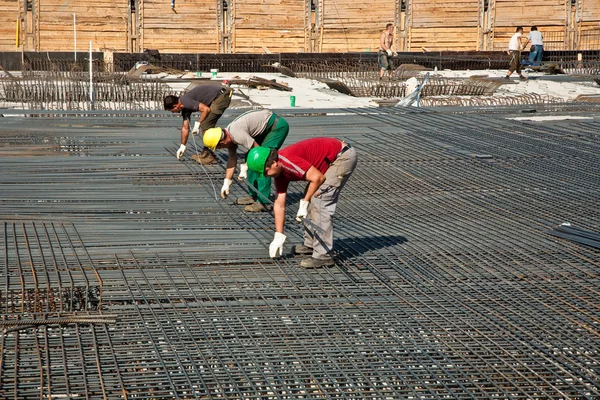 Рабочие вооружают фундаментную плиту здания железом — стоковое фото