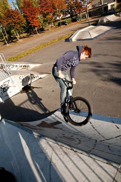 붉은 머리를 가진 어린 소년 스케이트 공원에 그의 자전거 점프 — 스톡 사진
