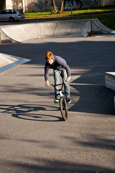 Νεαρό αγόρι με κόκκινα μαλλιά είναι το άλμα με το ποδήλατό του στο skate park — Φωτογραφία Αρχείου