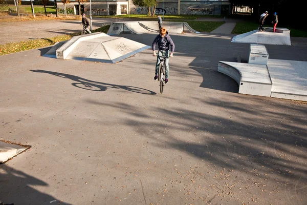 Menino com cabelo vermelho está pulando com sua bicicleta BMX no parque de skate — Fotografia de Stock