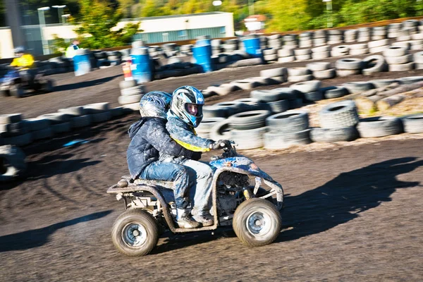 Criança adora correr com uma moto quad na pista quad lamacento — Fotografia de Stock