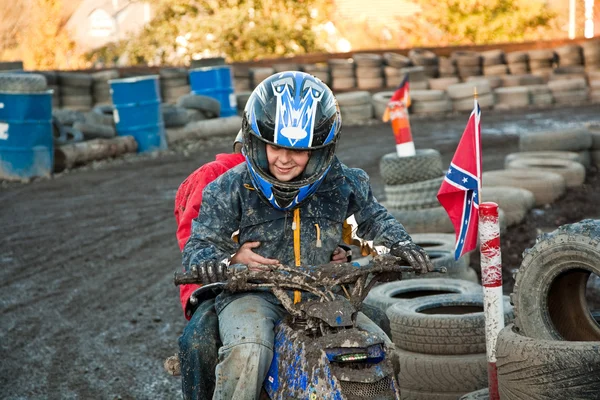 Niño le encanta correr con una bici cuádruple en la pista de cuádruple fangoso —  Fotos de Stock