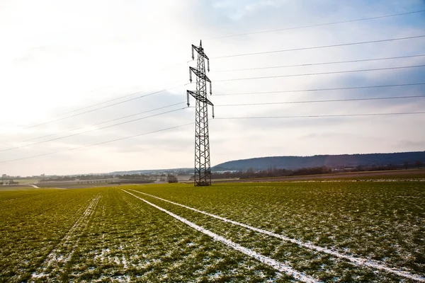 Mark van band in veld met elektrische toren in de winter — Stockfoto
