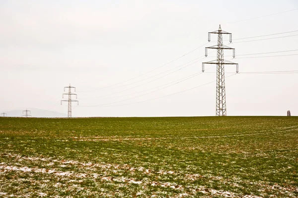 Marca de neumático en campo con torre eléctrica en invierno — Foto de Stock