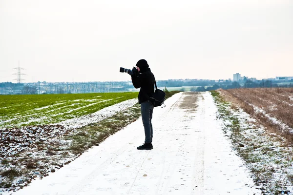 Мальчик фотографирует зимой в природе — стоковое фото