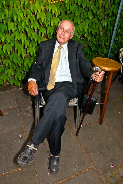 Eleganter älterer Mann, der nachts auf einem Stuhl sitzt — Stockfoto