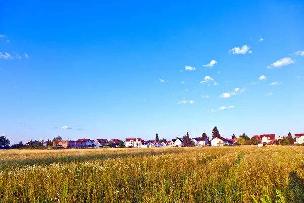 Nederzetting in landelijk gebied met velden onder de blauwe hemel — Stockfoto
