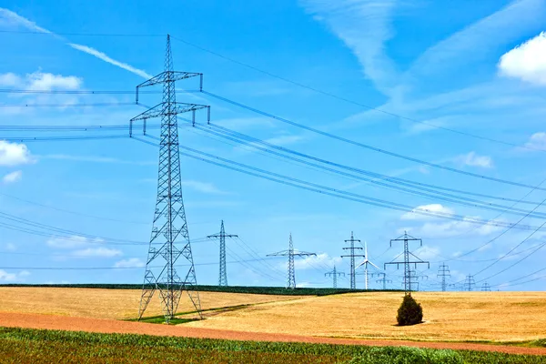 Лінія електропередачі з генератором вітру в сільському ландшафті — стокове фото