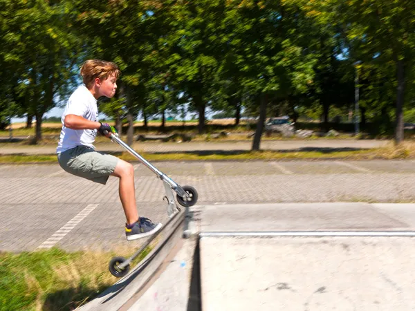 Jongen heeft plezier op de Skatepark met zijn scooter — Stockfoto