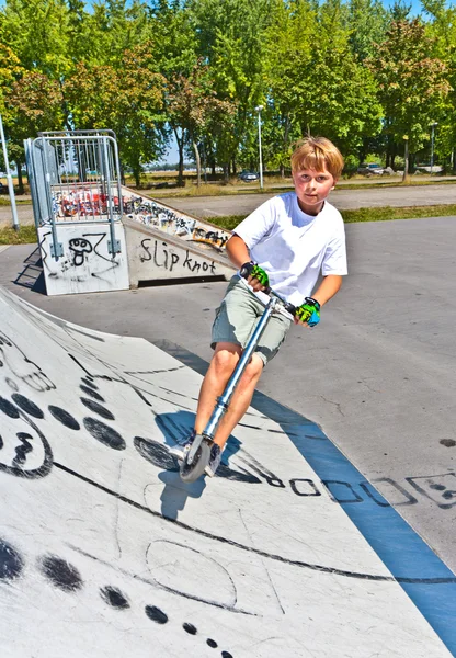Chico se divierte en el parque de skate con su scooter —  Fotos de Stock