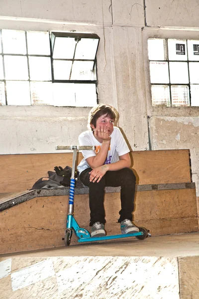 Уставший мальчик отдыхает от езды на скутере — стоковое фото