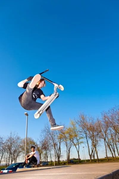 Menino pulando com sua scooter no céu — Fotografia de Stock