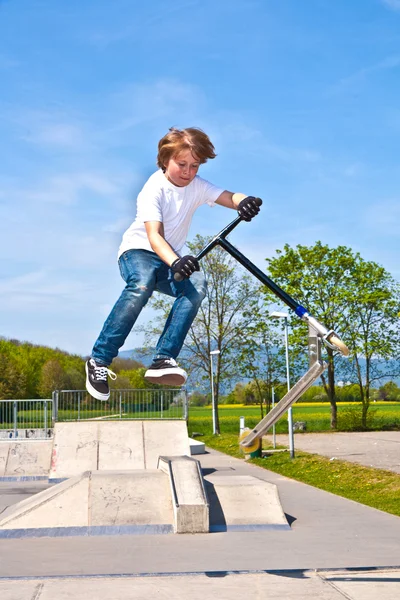 Chłopiec skaczący ze swoim skuterem na niebie — Zdjęcie stockowe