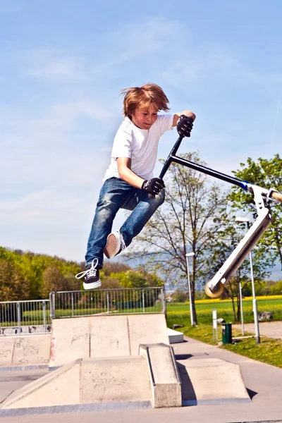 Boy jumping with his scooter in the sky — Stock Photo, Image